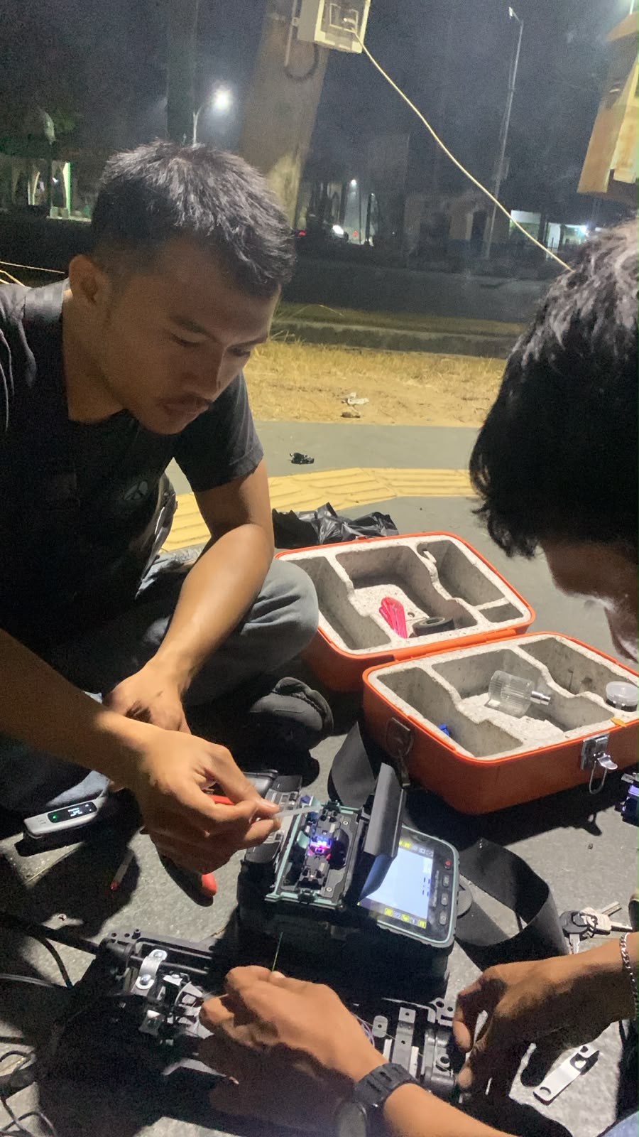 Teknisi menyambung fiber optik pada malam hari